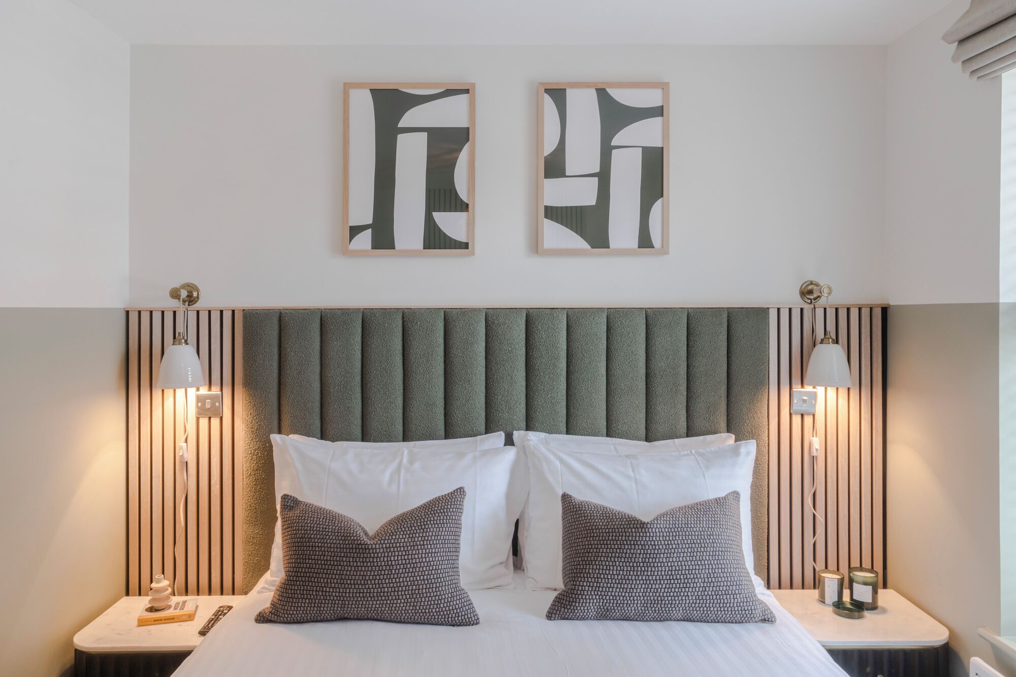 A neatly arranged hotel room with a large bed, two bedside tables, and abstract artwork on the wall.