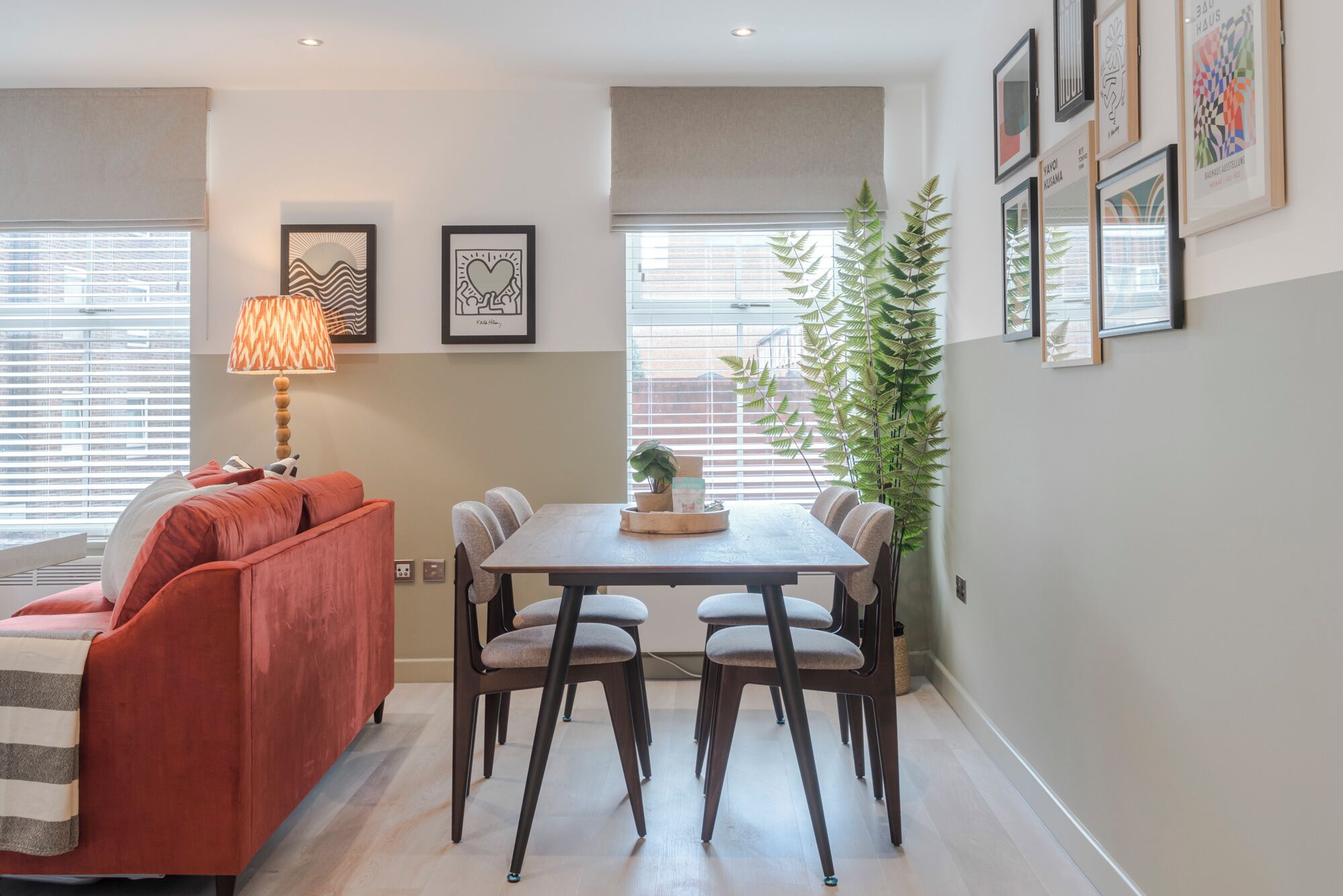 A dining area with a table and chairs, a sofa, and a lamp.