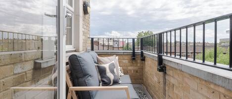 A balcony with a sofa, a glass door, and a view of the city.