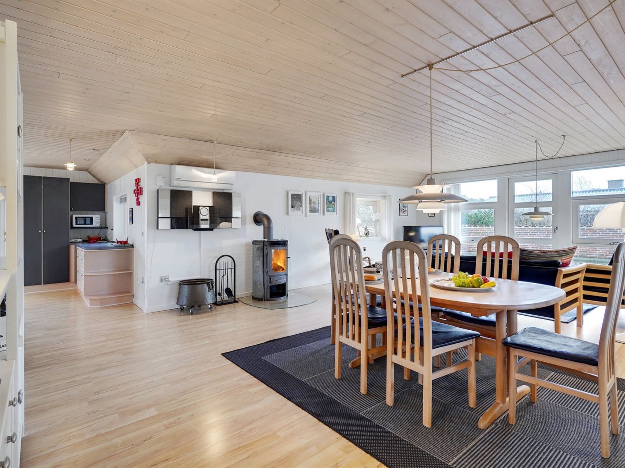A modern kitchen with a built-in stove, wooden dining table with chairs, and a large window providing natural light.