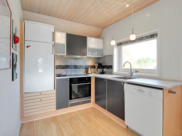 A modern kitchen with a built-in oven, a dishwasher, and a window providing natural light.
