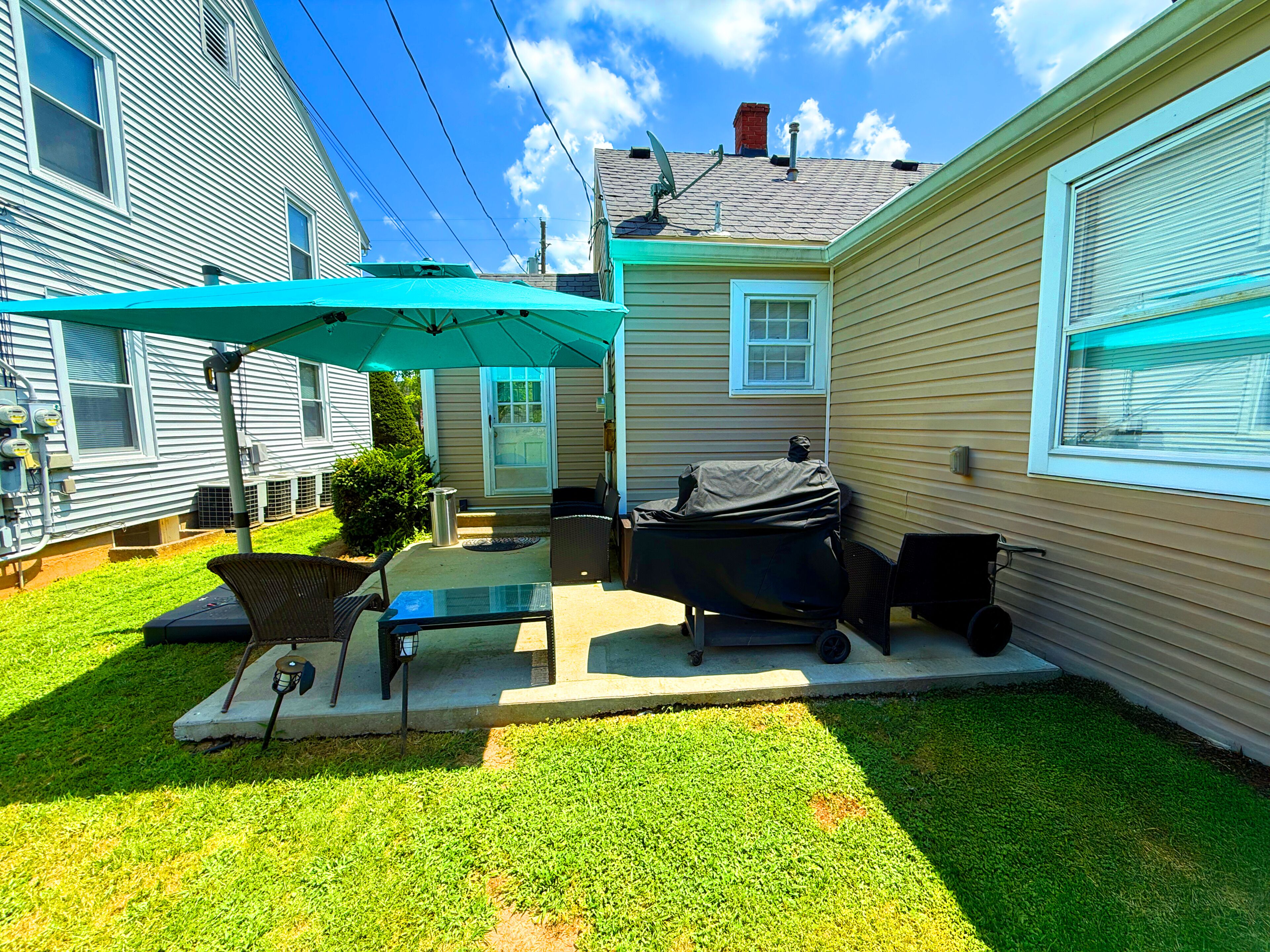 A backyard with a patio area, outdoor furniture, and a grill.