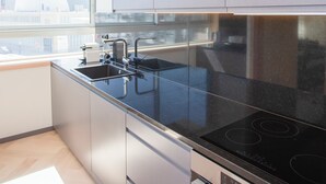 A modern kitchen with stainless steel appliances, a black countertop, and a window providing a view of the city. - Allegro Boutique Apartment 1A (Porto)