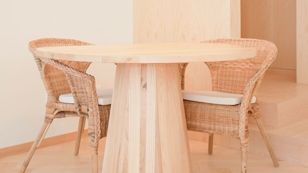 A round wooden table with two wicker chairs, a green pendant light, and a wooden floor. - Allegro Boutique Apartment 1A (Porto)
