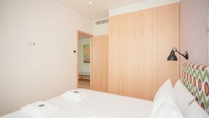 A hotel room with a bed, a wardrobe, and a bedside lamp. - Allegro Boutique Apartment 1A (Porto)