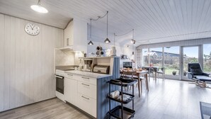 Una cocina moderna con una isla central, suelo de madera y una zona de comedor con vistas.