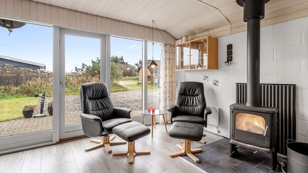 Una sala moderna con dos sillones de cuero, una mesa de vidrio y una chimenea de leña.