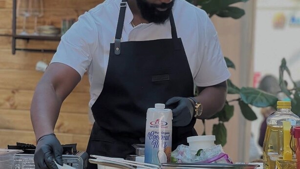 En person som lagar mat vid ett träbord med olika köksredskap och ingredienser.