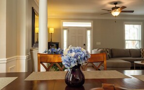 A dining area with a wooden table, a vase with flowers, and a ceiling fan.