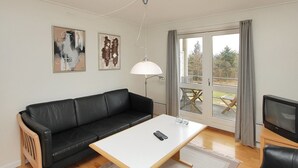 A modern living room with a black leather sofa, a white coffee table, a TV, and artwork on the wall. - "Enni" - 100m from the sea by Interhome (Hals)