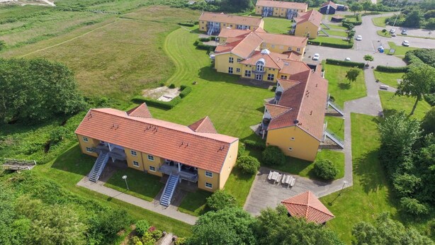 An aerial view of a residential area with multiple yellow buildings, a central staircase, and a parking area. - "Enni" - 100m from the sea by Interhome (Hals)