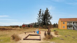 A sandy play area with a slide and a swing, surrounded by grass and rocks. - "Enni" - 100m from the sea by Interhome (Hals)