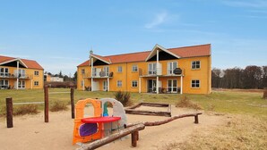 A yellow building with a red roof, a playground, and a sandy area. - "Enni" - 100m from the sea by Interhome (Hals)