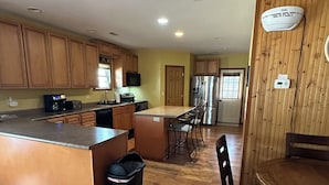 Una cocina amplia con armarios de madera, una isla central y una zona de comedor con una mesa redonda y sillas.