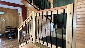 Una escalera de madera con barandilla de metal en una habitación con pisos y paredes de madera.