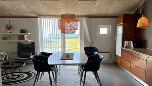 A modern kitchen with a dining area, featuring a round table, black chairs, and a hanging light fixture.