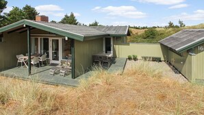 Een laag, enkelvoudig gebouw met een groen dak en een overdekt terras. Er zijn zitgedeeltes buiten en een kleine tuin.