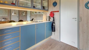 Een moderne keuken met blauwe kastjes, een houten plafond en een deur met een ronde greep.