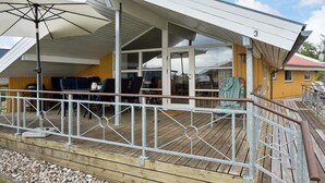 A covered outdoor area with a wooden deck, metal railing, and a large umbrella. - "Hjalmar" - 400m from the sea by Interhome (Millinge)