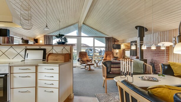 A modern kitchen with white cabinets, a built-in oven, and a dining area with a table and chairs. - "Hjalmar" - 400m from the sea by Interhome (Millinge)