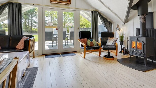 Une pièce chaleureuse avec un plafond en bois, une cheminée, un canapé et un coin repas comprenant des chaises et une table.