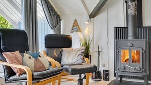 Un salon moderne avec un canapé en cuir noir, un fauteuil à bascule en bois et un poêle à bois noir.