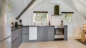 Une cuisine moderne dotée d’un grand îlot central, d’appareils électroménagers intégrés et d’un plafond en pente.