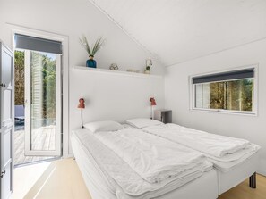 Ein Schlafzimmer mit Bett, Fenster, Tür und einem Regal mit Pflanzen.