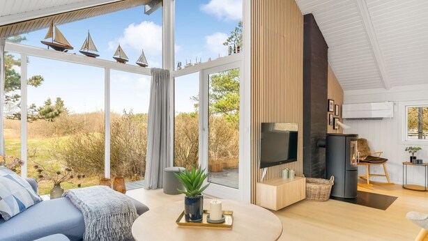 Een moderne woonkamer met een groot raam, een televisie, een open haard en een bank.