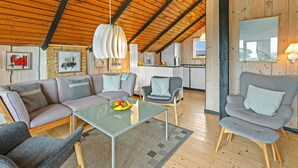 A spacious living area with a high wooden ceiling, a glass coffee table, and a kitchen in the background. - "Hildegart" -  from the sea by Interhome (Hvide Sande)