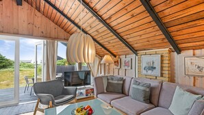 A cozy living room with a wooden ceiling, a sofa, a TV, and a glass table with fruit. - "Hildegart" -  from the sea by Interhome (Hvide Sande)