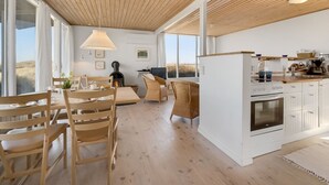 A spacious living area with a wooden ceiling, large windows, and a central fireplace. - "Vina" - 200m to the fjord by Interhome (Hvide Sande)