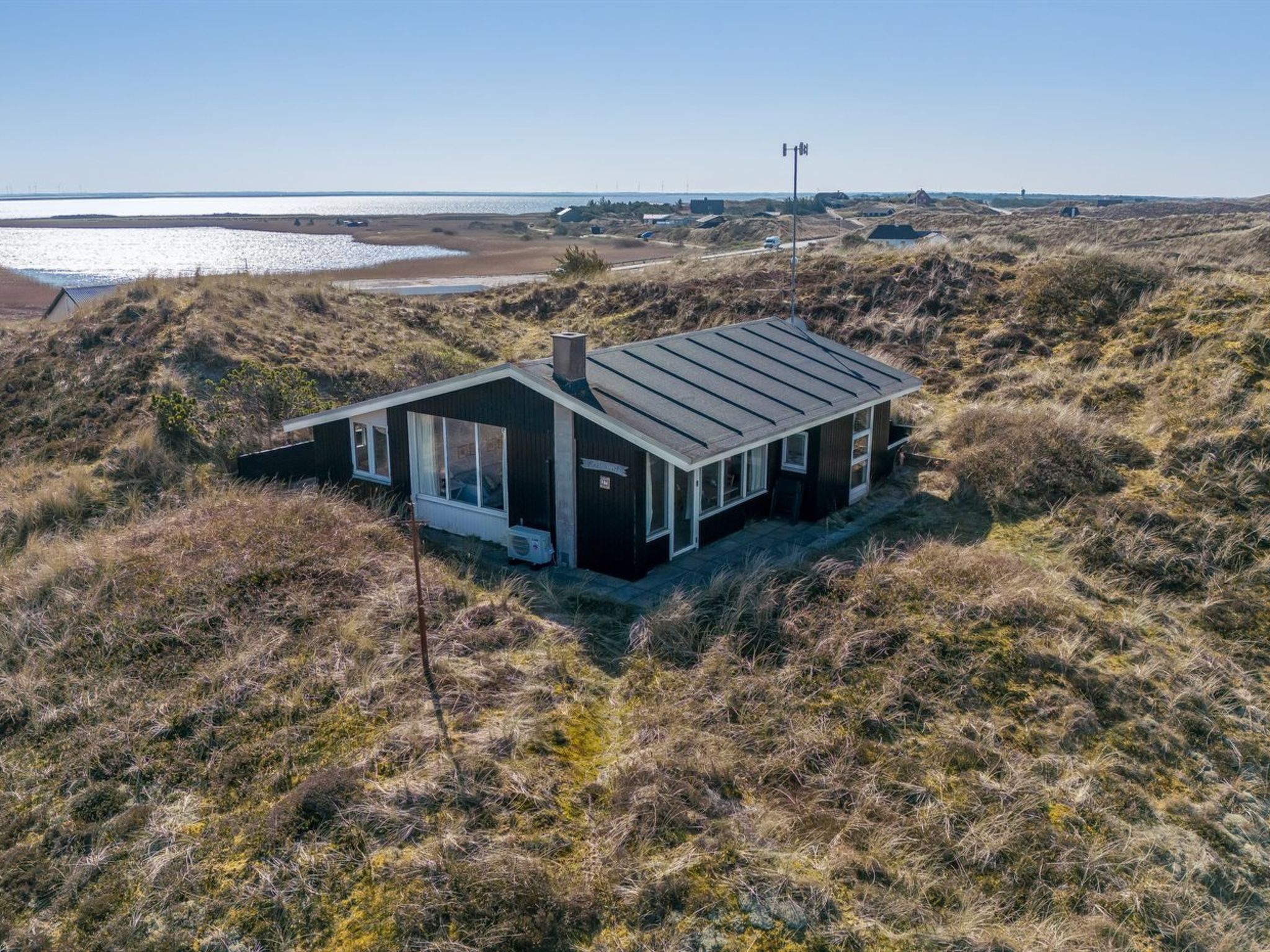 A modern house with a sloped roof, large windows, and a view of the surrounding landscape.
