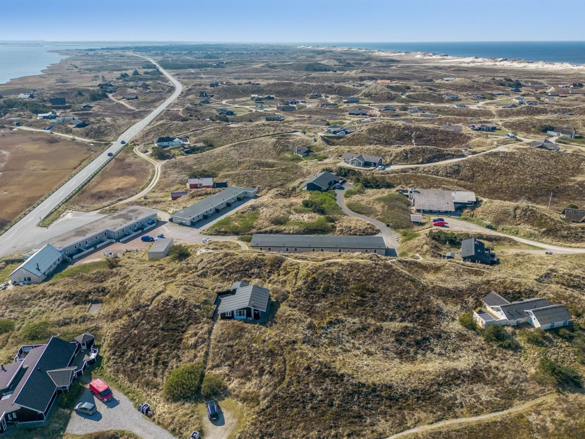 An aerial view of a coastal area with scattered buildings, roads, and a beach.