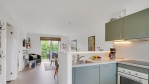 A modern kitchen with a central island, a built-in oven, and a dining area with a view of the outdoors. - "Sipi" - 100m from the sea by Interhome (Hals)