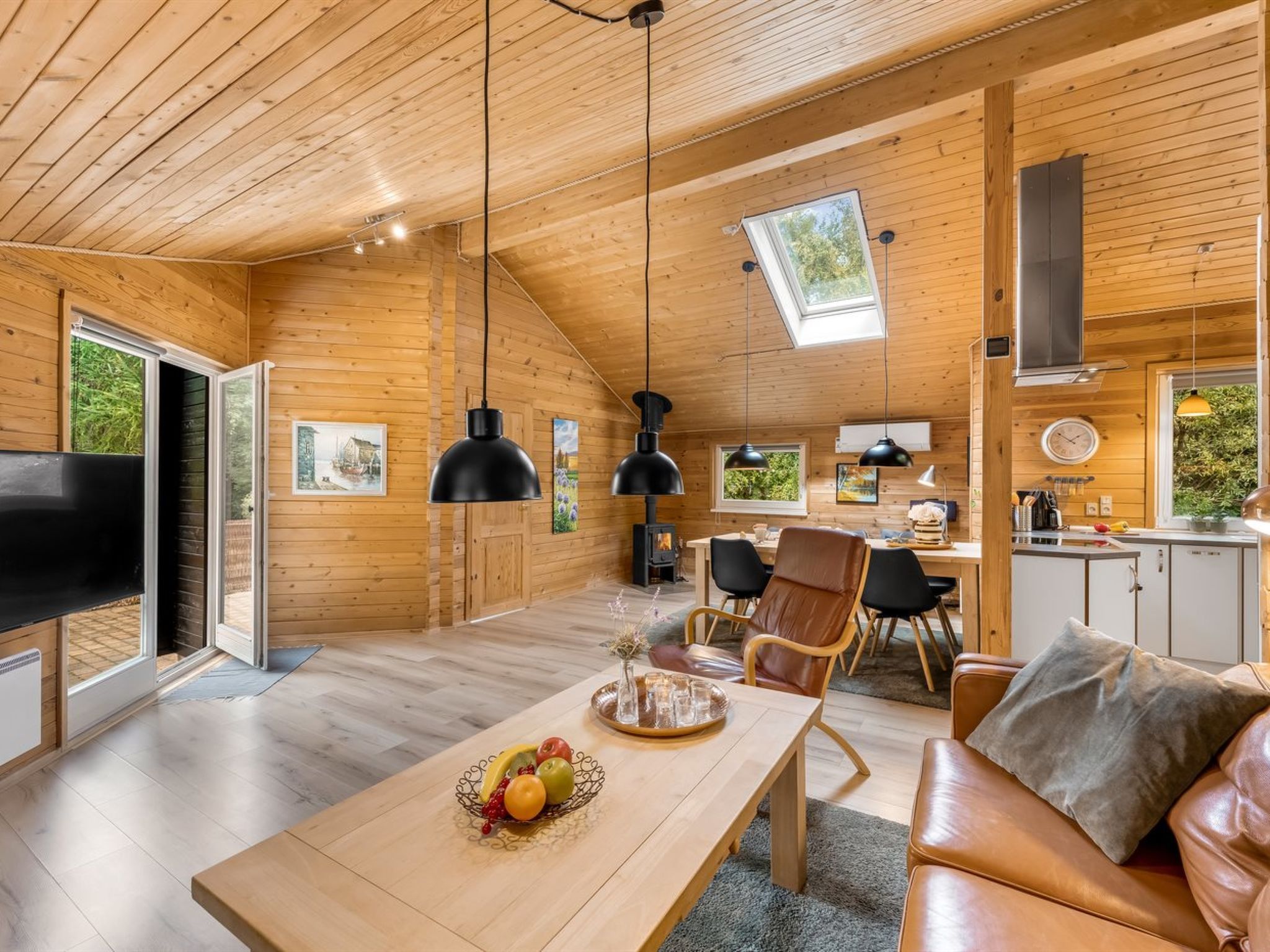 L’intérieur chaleureux d’un chalet comprend un coin repas, un salon avec un canapé et une cuisine équipée d’une cuisinière.