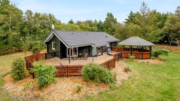 A cabin with a deck, a covered patio, and a fenced yard. - "Jorina" - 700m to the fjord by Interhome (Ringkøbing)