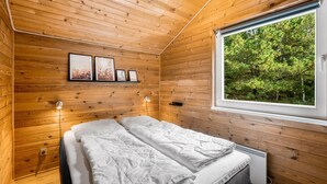 A wooden-paneled room with a bed, a window, and wall-mounted lights. - "Jorina" - 700m to the fjord by Interhome (Ringkøbing)