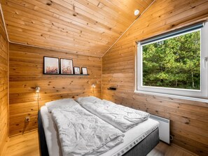Una habitación con paneles de madera, una cama, una ventana y luces fijadas a la pared.