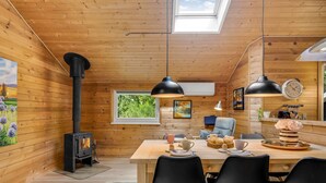 A cozy cabin interior with a wooden interior, a dining table set for four, and a wood-burning stove. - "Jorina" - 700m to the fjord by Interhome (Ringkøbing)