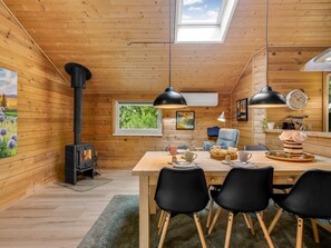 Interior acogedor de una cabaña con detalles de madera, una mesa de comedor para cuatro personas y un estufa de leña.