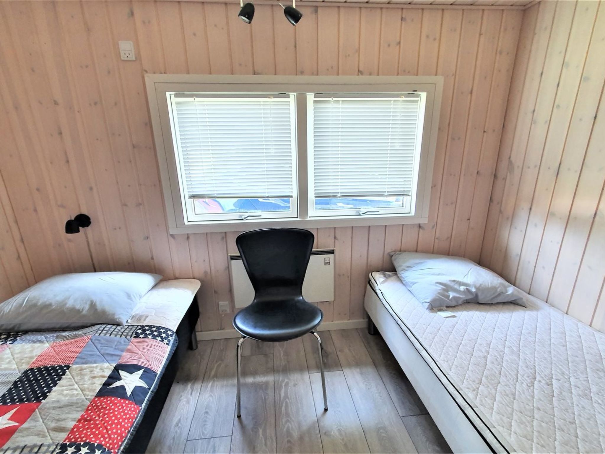 A small, cozy room with two beds, a desk, and a chair.