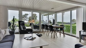 Een moderne woonkamer met een groot raam, een eethoek en een tv-meubel.