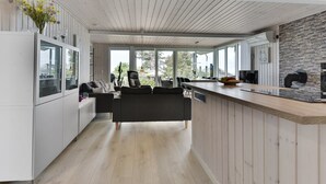 Een moderne keuken met een houten plafond, een eethoek met een zwarte bank en een betegelde muur.