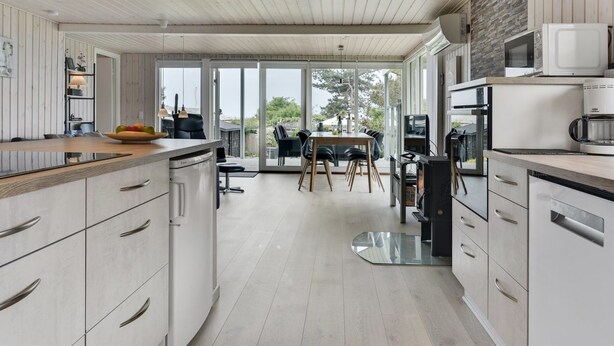Een moderne keuken met een centraal eiland, ingebouwde apparatuur en een eetgedeelte met uitzicht.