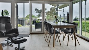 Een moderne eetruimte met een grote tafel en stoelen, grote ramen en uitzicht op het omliggende landschap.