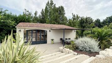 A modern house with a tiled roof, a covered patio, and a stone staircase leading to a door.