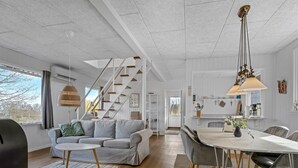 Ein modernes Wohnzimmer mit Sofa, Esstisch und Treppe.