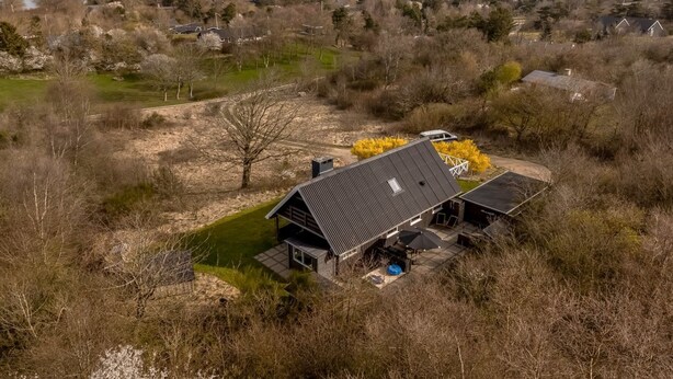 Ein Haus mit geneigtem Dach, einer Terrasse mit Gartenmöbeln und Blick auf das Meer.