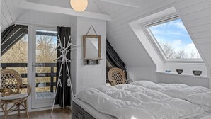 Ein Schlafzimmer mit einem großen Bett, einem Oberlicht, einem Fenster, einem Spiegel und einem Stuhl.